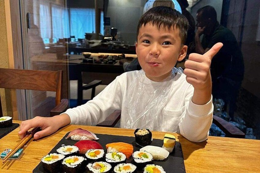 Une personne assise à une table devant une variété de plats de sushis. 2