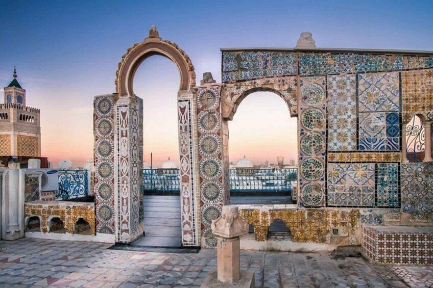 A tiled archway with intricate patterns, leading to a view of a bridge and a mosque with a minaret. 2