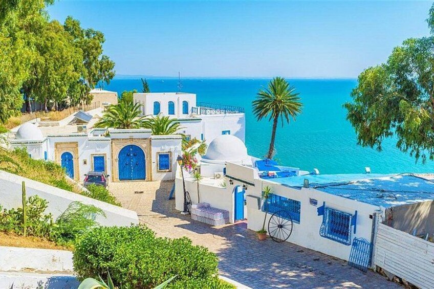 A coastal village with white buildings, blue doors, and a clear view of the sea. 1
