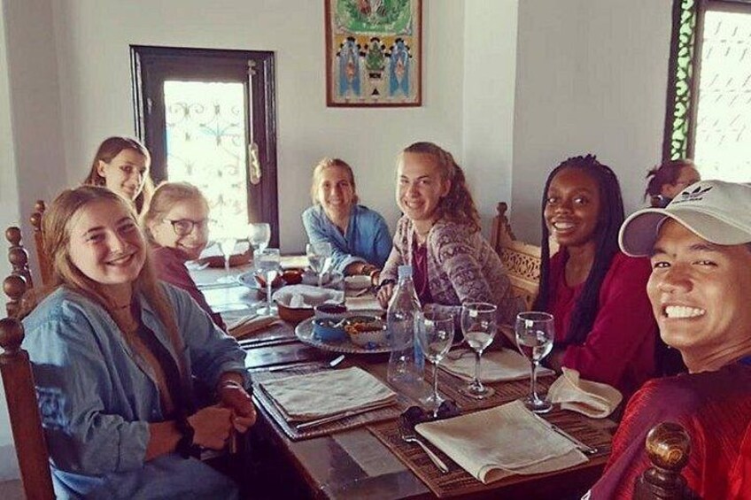 A group of people sitting around a table with wine glasses and plates. 4