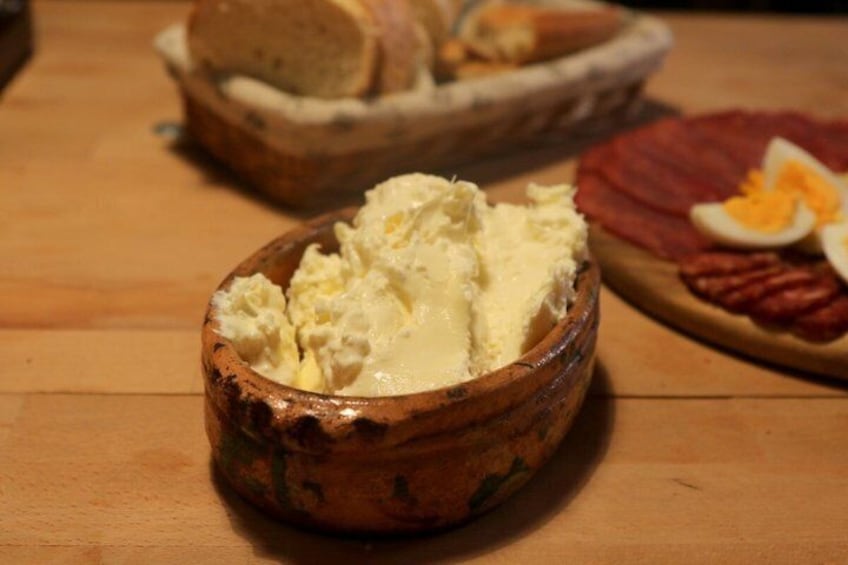 A wooden bowl with a creamy substance, possibly butter, on a wooden table. 5