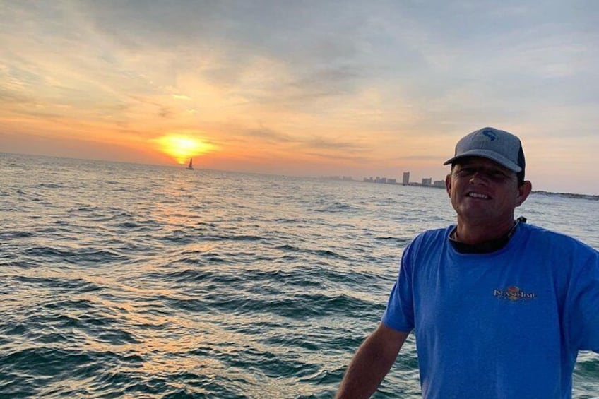A person standing on a boat with a sunset in the background. 4