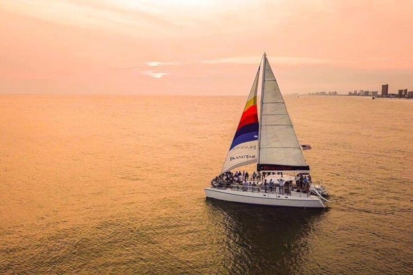 A sailboat with a colorful sail on the water during sunset. 1