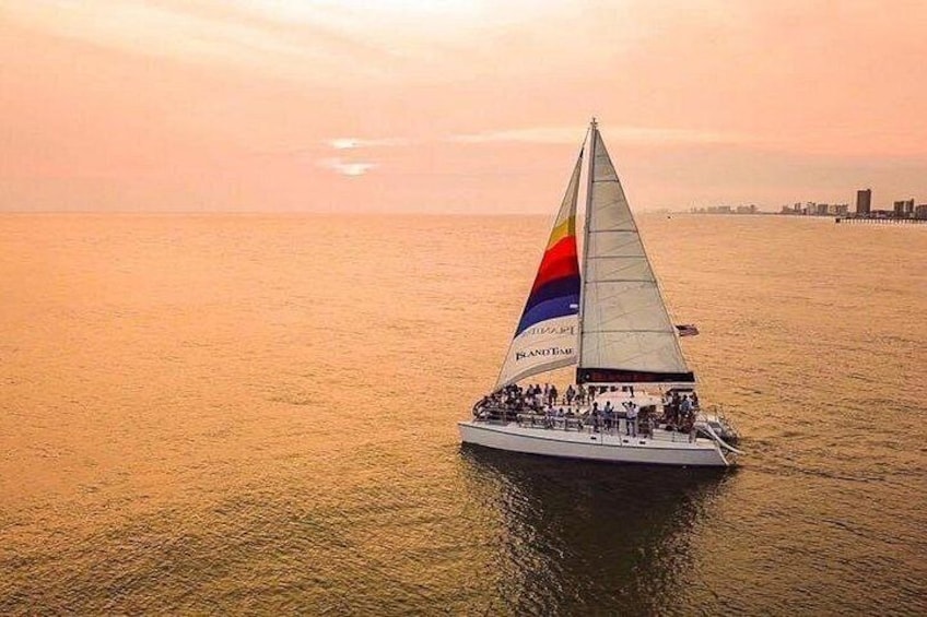 A sailboat with a colorful sail on the water during sunset. 1