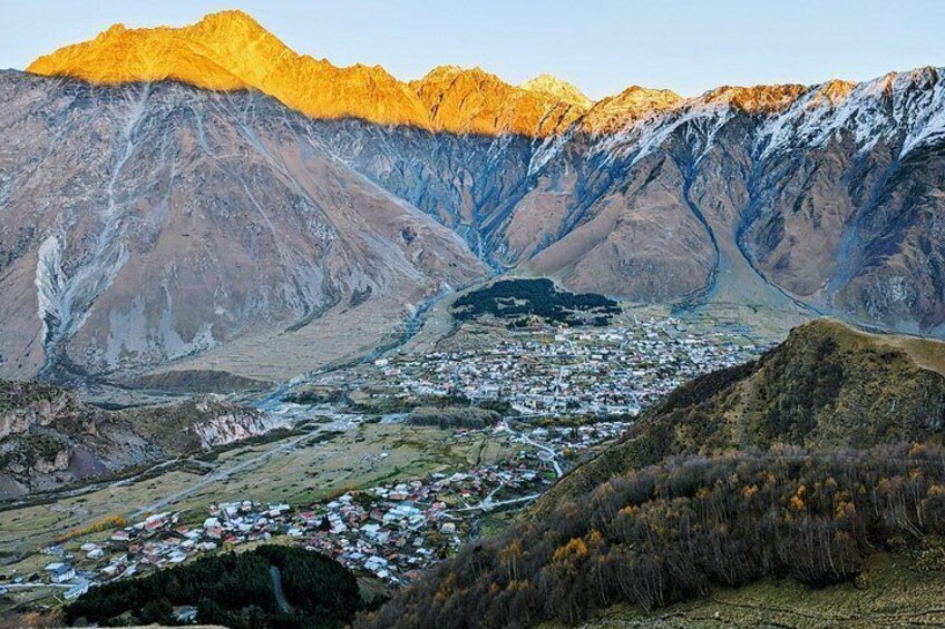 A mountainous landscape with a valley, a small town, and snow-capped peaks. 2