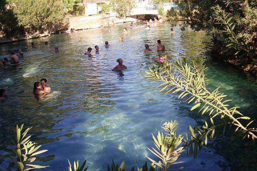 Una piscina cristalina con gente nadando y disfrutando, rodeada de vegetación. 2