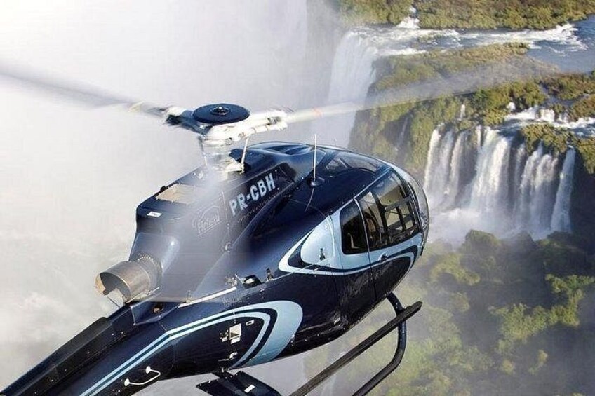 Un helicóptero con el número de registro PR-CBH volando sobre una cascada. 2
