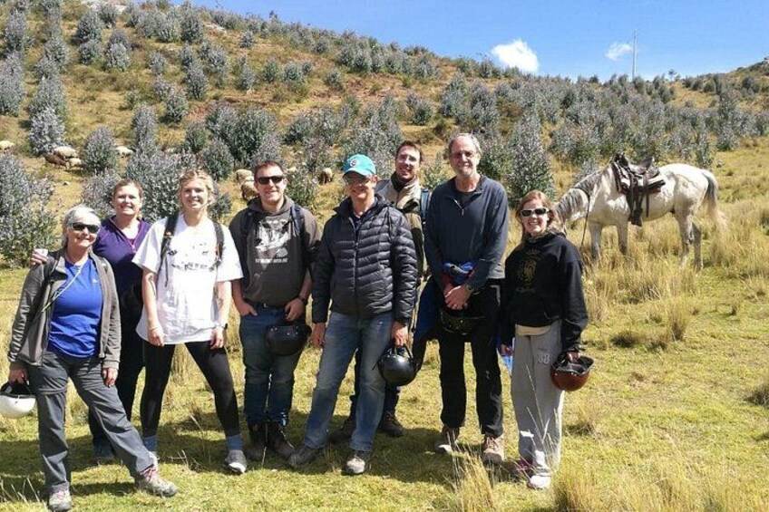 A group of people standing in a grassy field with a horse in the background. 3