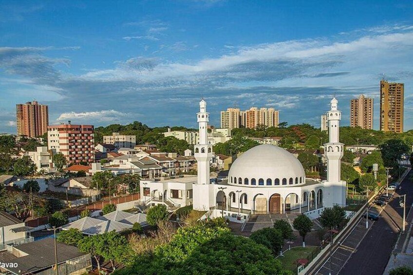 Une mosquée dotée d’un grand dôme et de deux minarets, entourée d’immeubles d’habitation et s’élevant vers un ciel dégagé. 5