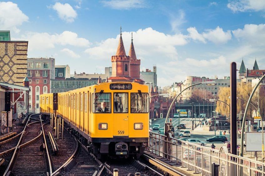 Un tranvía amarillo sobre rieles, con un paisaje urbano de fondo. 1