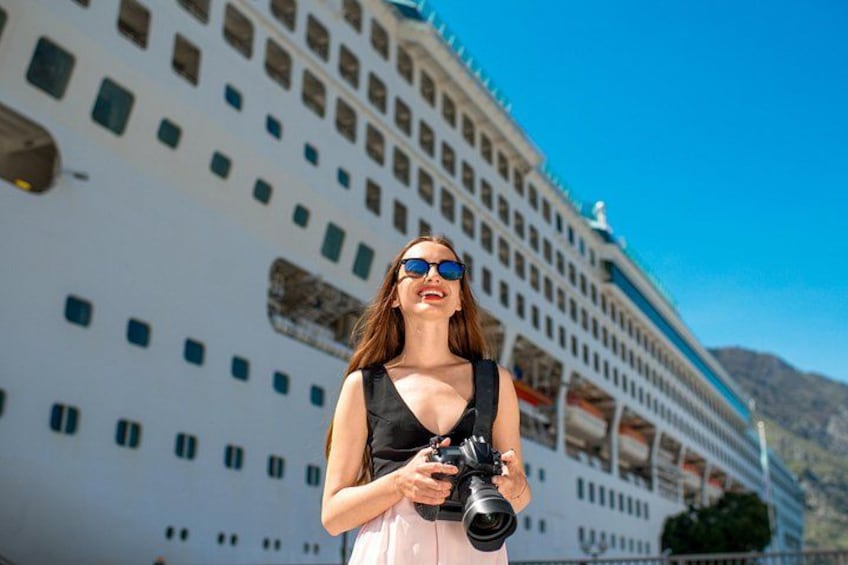 Una persona sosteniendo una cámara frente a un gran crucero. 4