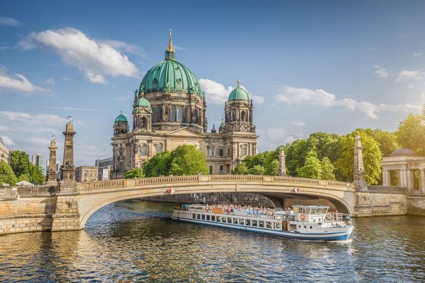 A river with a bridge, a boat, and a historic building with green domes. 1