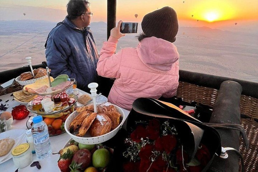 Una pareja cenando en una mesa con vistas panorámicas al atardecer. 3
