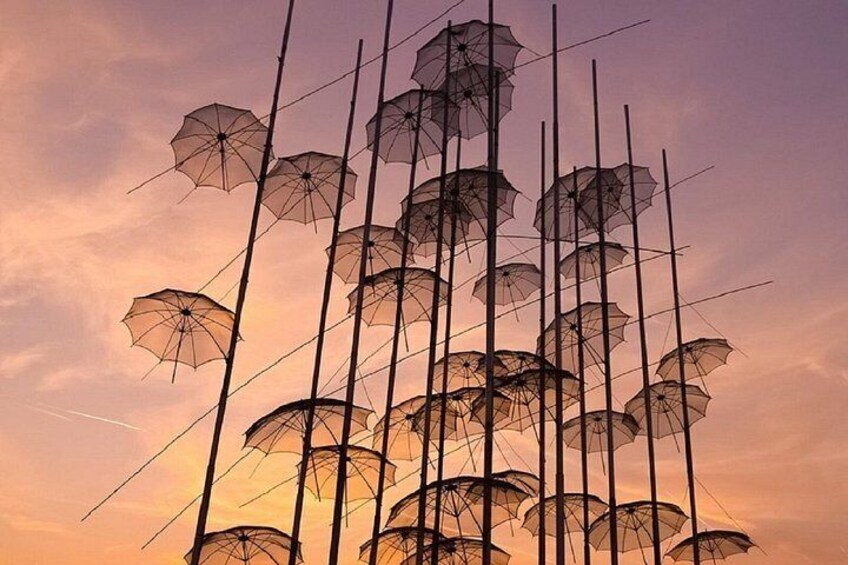 Une collection de parapluies disposés en une structure verticale sur fond de ciel au coucher du soleil. 2