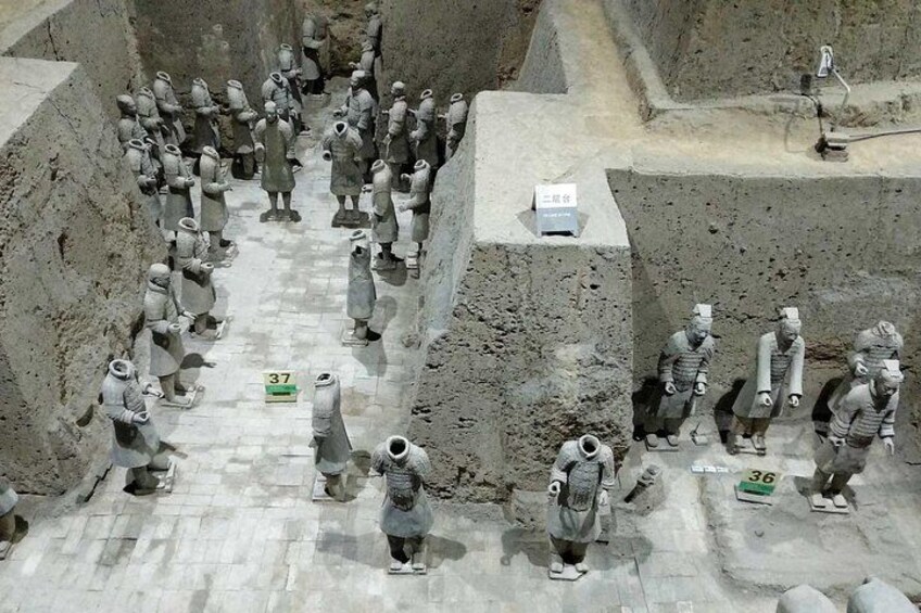 A large number of terracotta soldiers arranged in a formation, with some figures holding spears and others carrying objects. 2