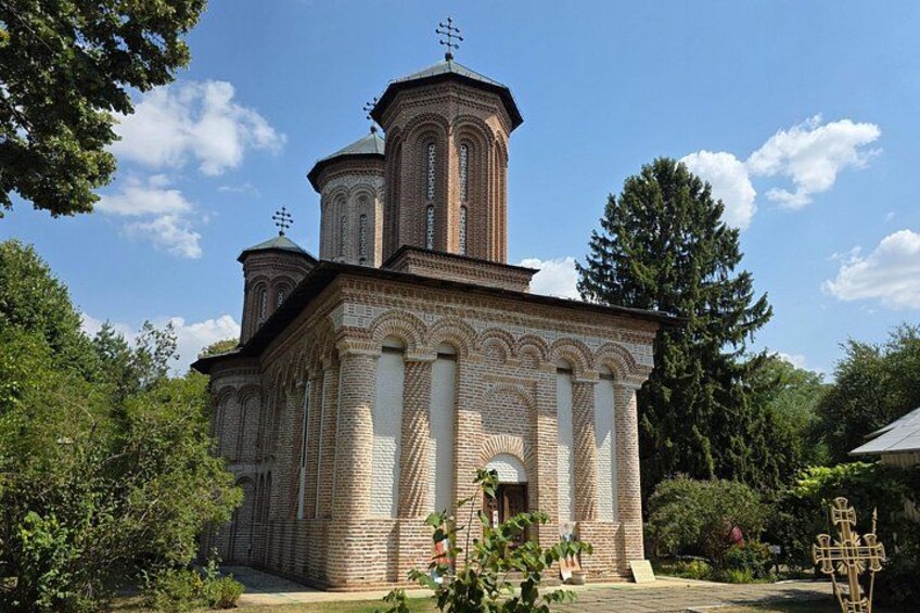 A brick church with multiple domes and crosses, surrounded by trees and greenery. 2