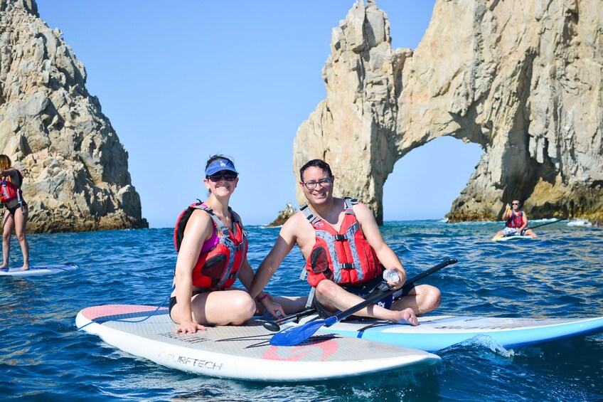Two people on paddleboards in a rocky bay with clear skies. 1