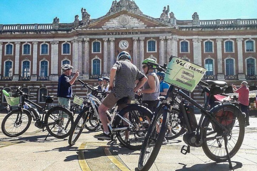 A group of cyclists in front of a historic building with a sign that reads 'Velkommen.' 1