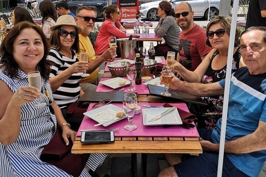 Des personnes sont assises à une table, devant des boissons, une nappe rose et une bouteille de bière. 5