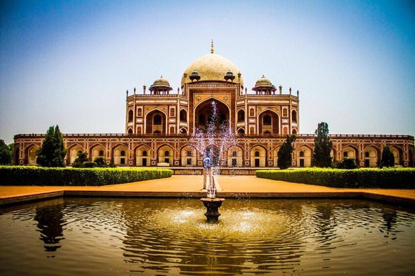 A large, historic building with a central dome and arched windows, surrounded by a reflective water body and well-manicured greenery. 2