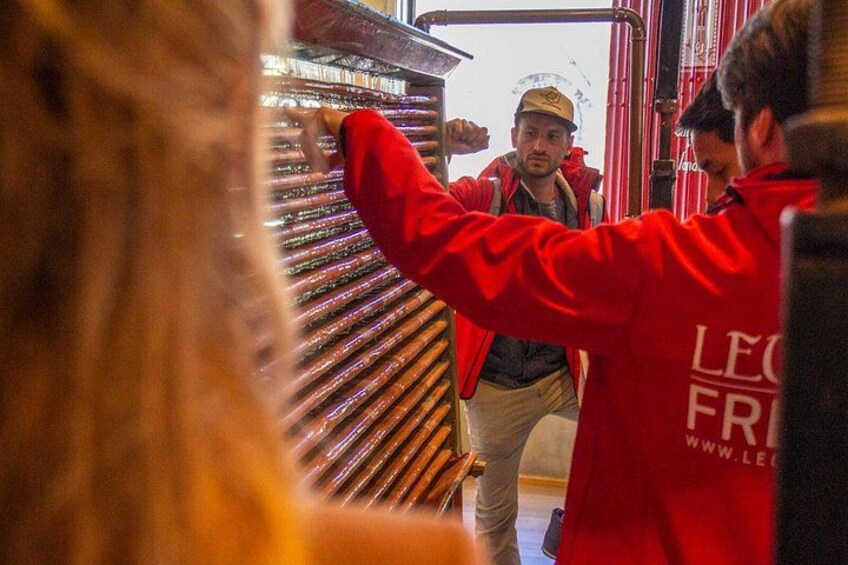 Une personne vêtue d’une veste rouge interagit avec une grande structure métallique, qui pourrait être un élément d’équipement industriel. 2
