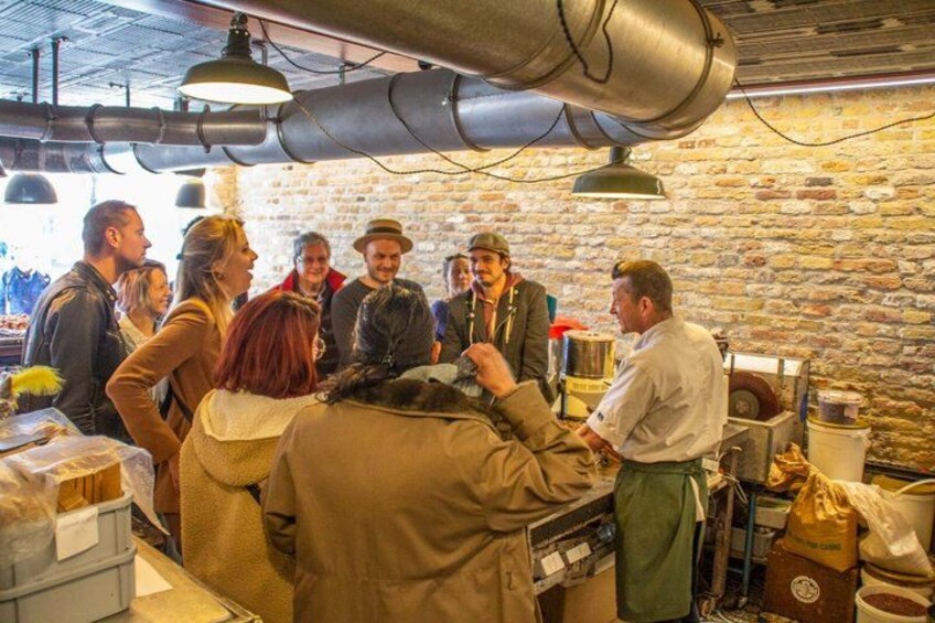 Un grupo de personas en una cocina rústica con paredes de piedra y elementos industriales como tuberías y una estufa. 4