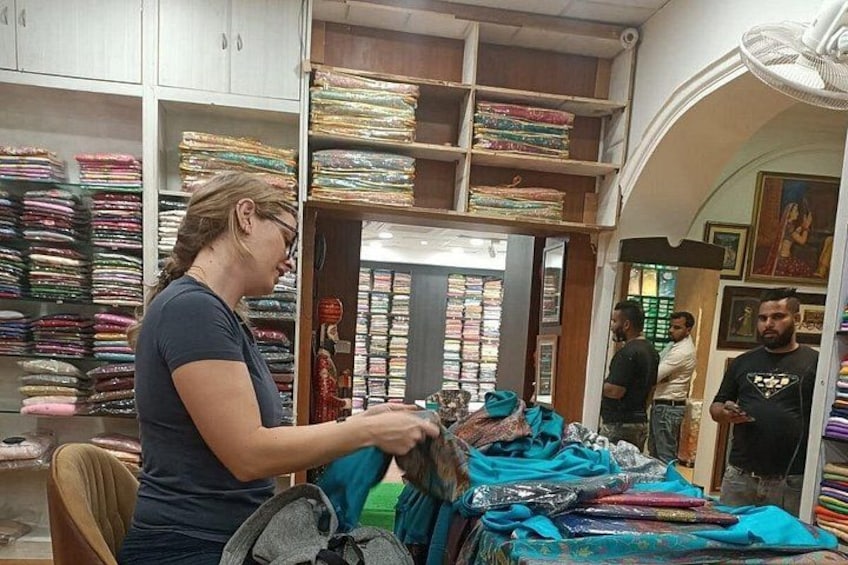 A person working with textiles in a shop with shelves of folded fabrics. 2