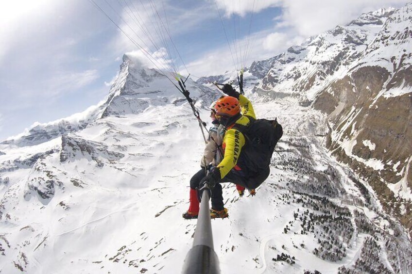 A person paragliding over a snowy mountain landscape. 1