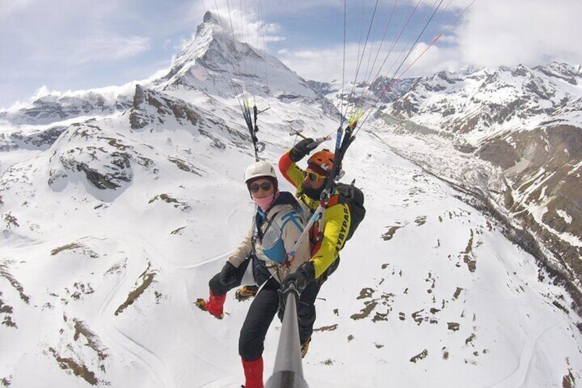 Two people paragliding on a snowy mountain with a clear sky. 4