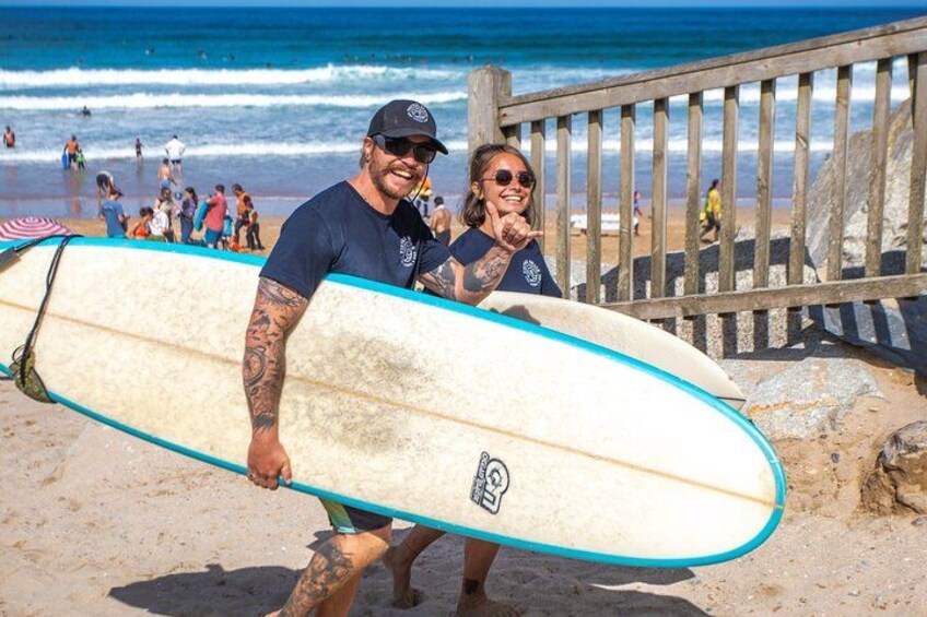 A man holding a surfboard on a beach with people in the background. 2