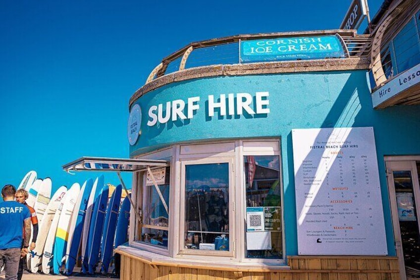 A surf hire kiosk with surfboards and a menu board. 1
