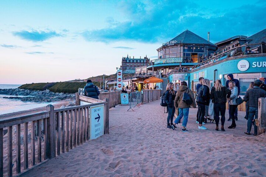 A beachside promenade with people walking, a sign pointing to the right, and a building with a 'SURF' sign. 3