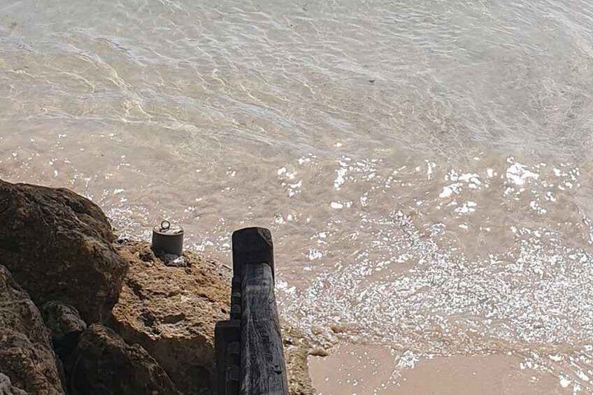 A rocky shoreline with a wooden post and a pot on the rocks. 5