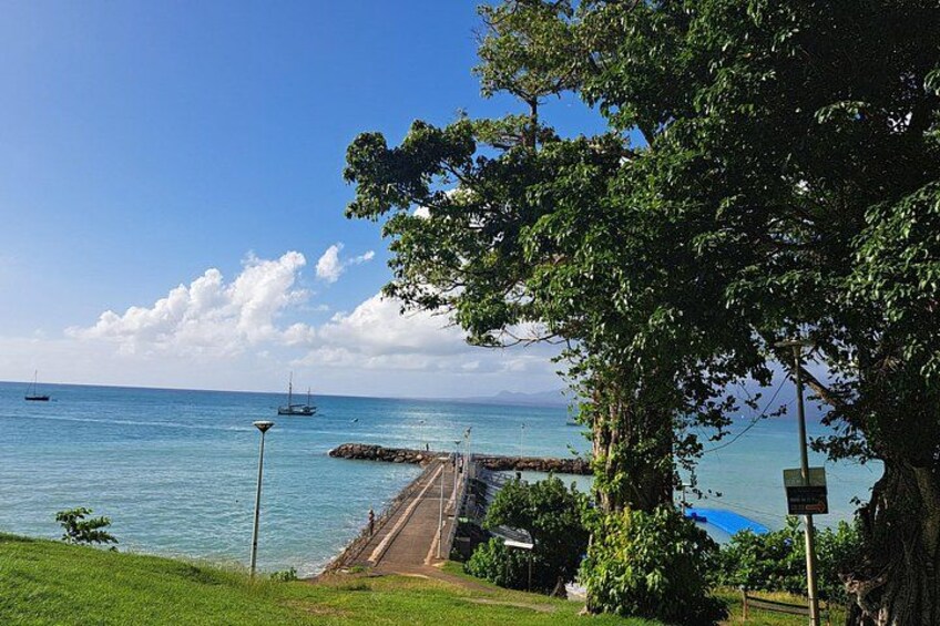 A coastal scene with a pier extending into the water, a clear sky, and a distant boat. 2