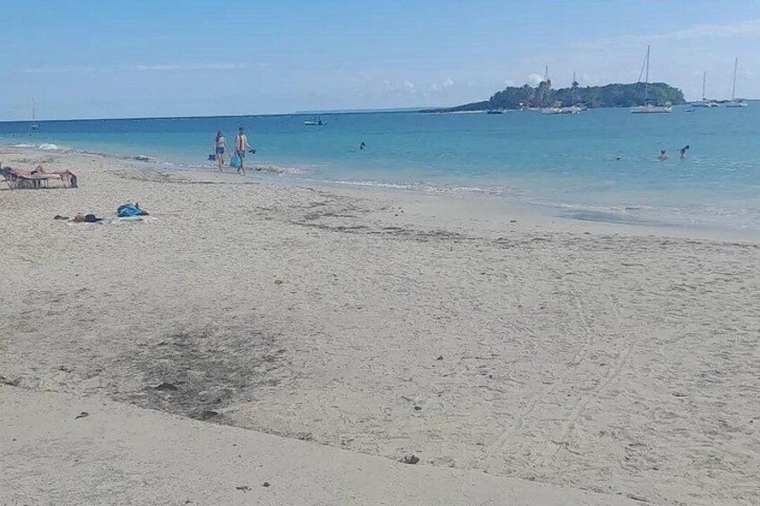 A beach with people walking, a sandy shore, and boats in the water. 4