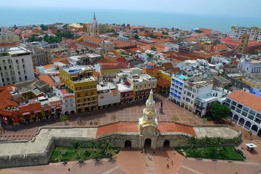 A coastal cityscape with a prominent fort, colorful buildings, and a distant church spire. 3