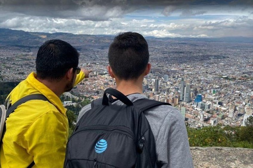 Two people overlooking a cityscape with mountains in the background. 2