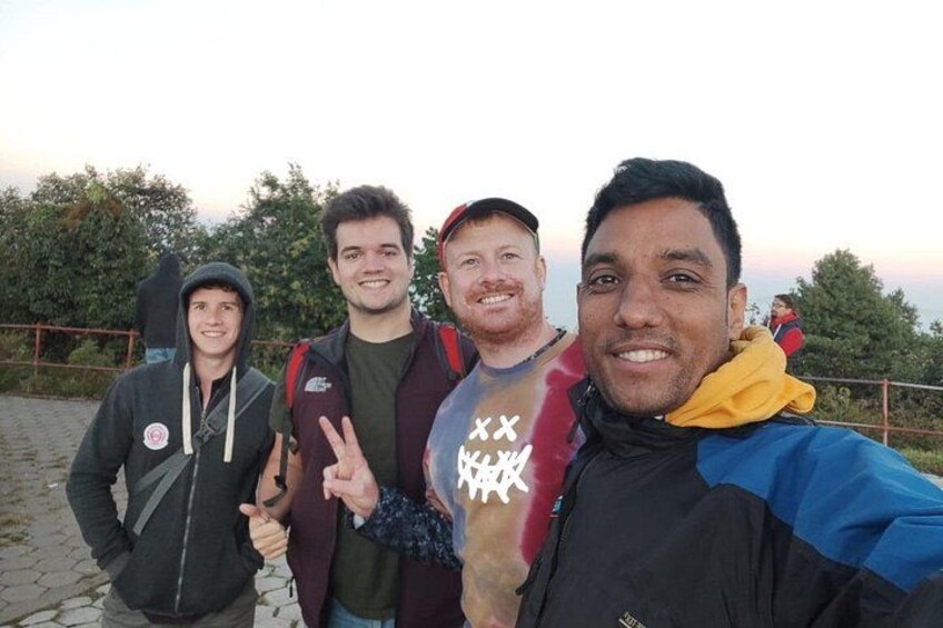 Vier personen staan op een geplaveid pad, met bomen op de achtergrond. 3