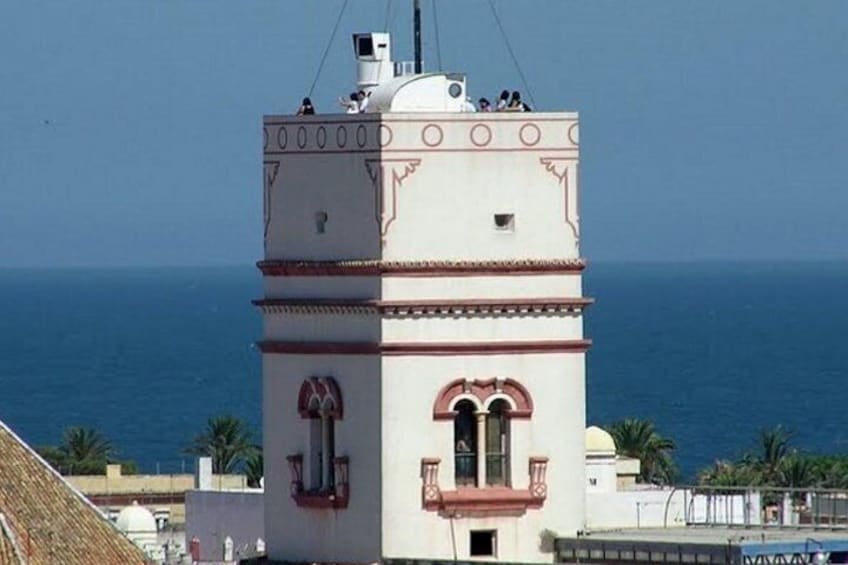 Ein weißer Turm mit roter Umrandung und einem Balkon mit Blick auf das Meer. 1