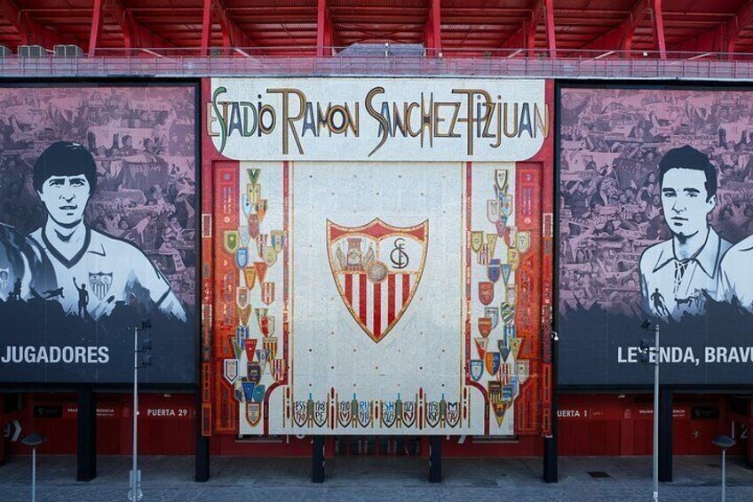 Een stadion met een muurschildering van een voetballer, het logo van de club en trofeeën. 5