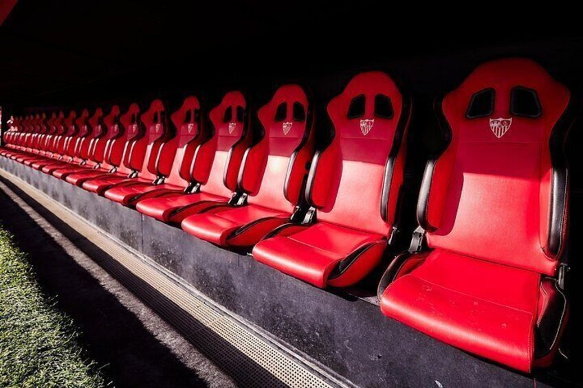 Een rij rode stoelen in een stadion, met een logo op de rugleuningen. 4