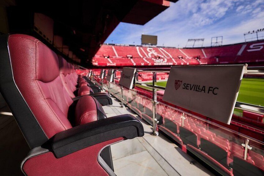 Stadiontribunes in rood en zwart, een heldere lucht en een spandoek met de tekst 'SEVILLA FC'. 3