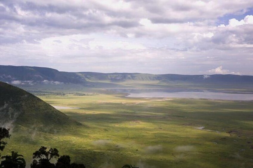 A vast landscape with rolling hills, a large body of water, and a cloudy sky. 2