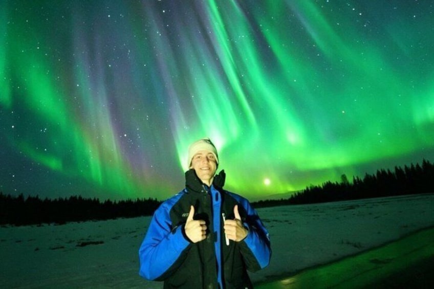 A person standing in a snowy landscape under a night sky with green aurora borealis. 1