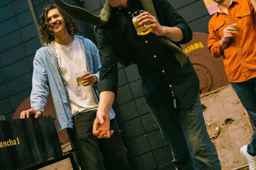 Een persoon in een zwart shirt met een drankje, een ander in een lichtblauw shirt, en een derde in een oranje shirt. 4