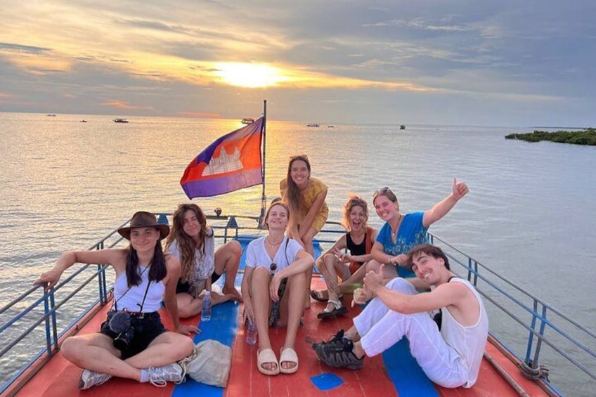 Un gruppo di persone su una barca con una bandiera, tramonto sullo sfondo. 2