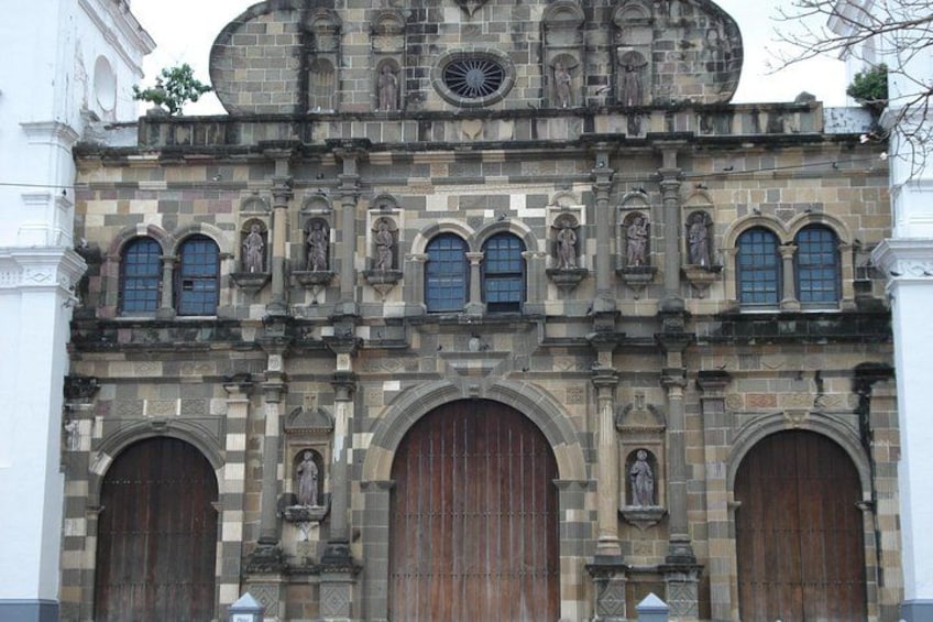 A historic building with ornate stonework, large wooden doors, and statues. 1