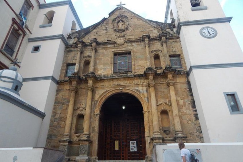 A historic building with a large arched entrance, a clock tower, and a person walking in front. 3
