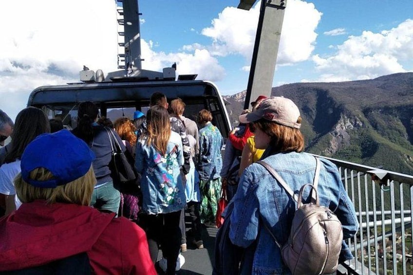 A group of people standing on a bridge with a mountainous landscape in the background. 5