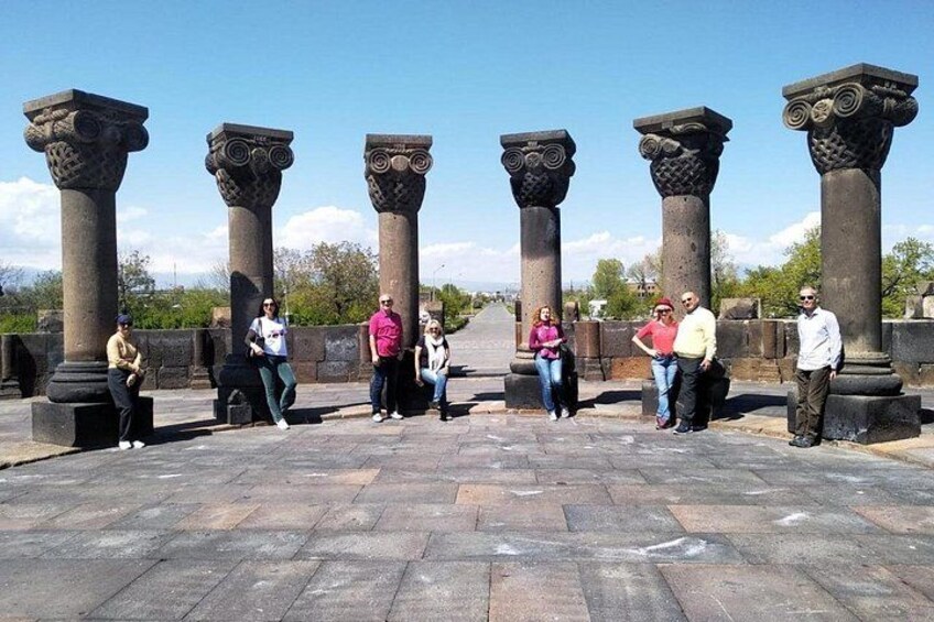 A group of people standing in front of ancient stone columns with intricate carvings. 4